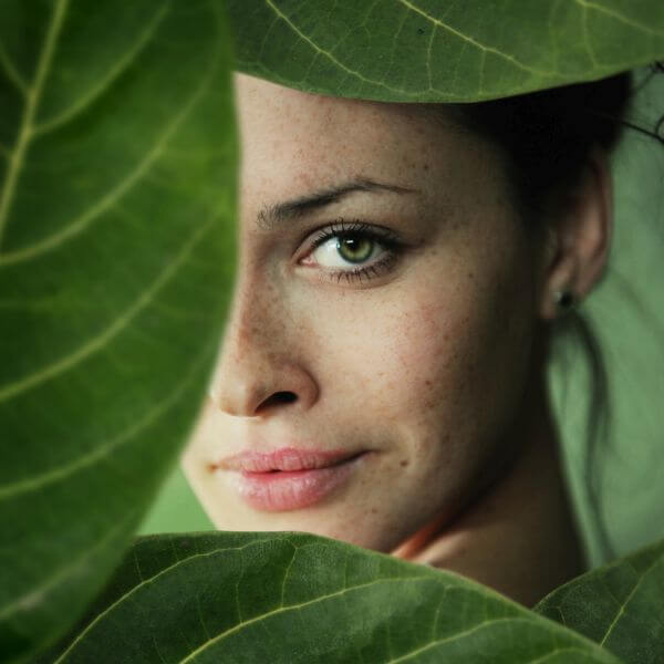 a close-up portrait of young beautiful women in leaf frame